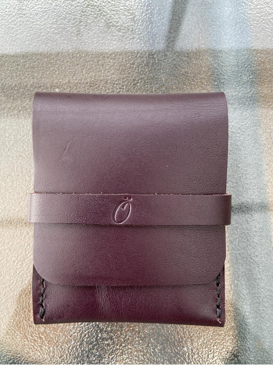 Handmade oxblood leather card wallet with snap strap and stamped logo